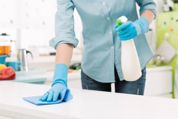 Wiping down a kitchen counter with sanitizer